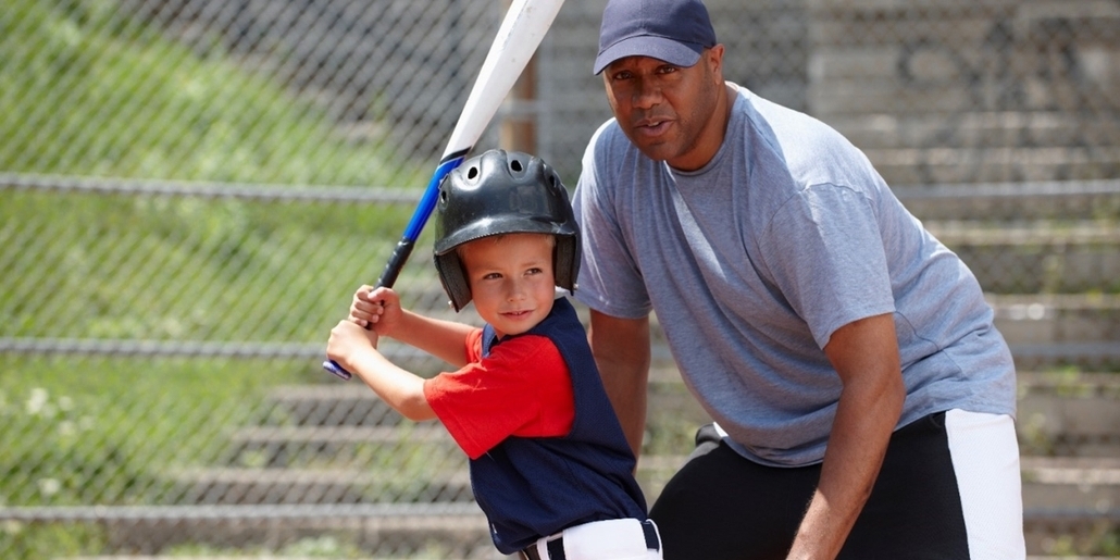 man coaching boy to play baseball